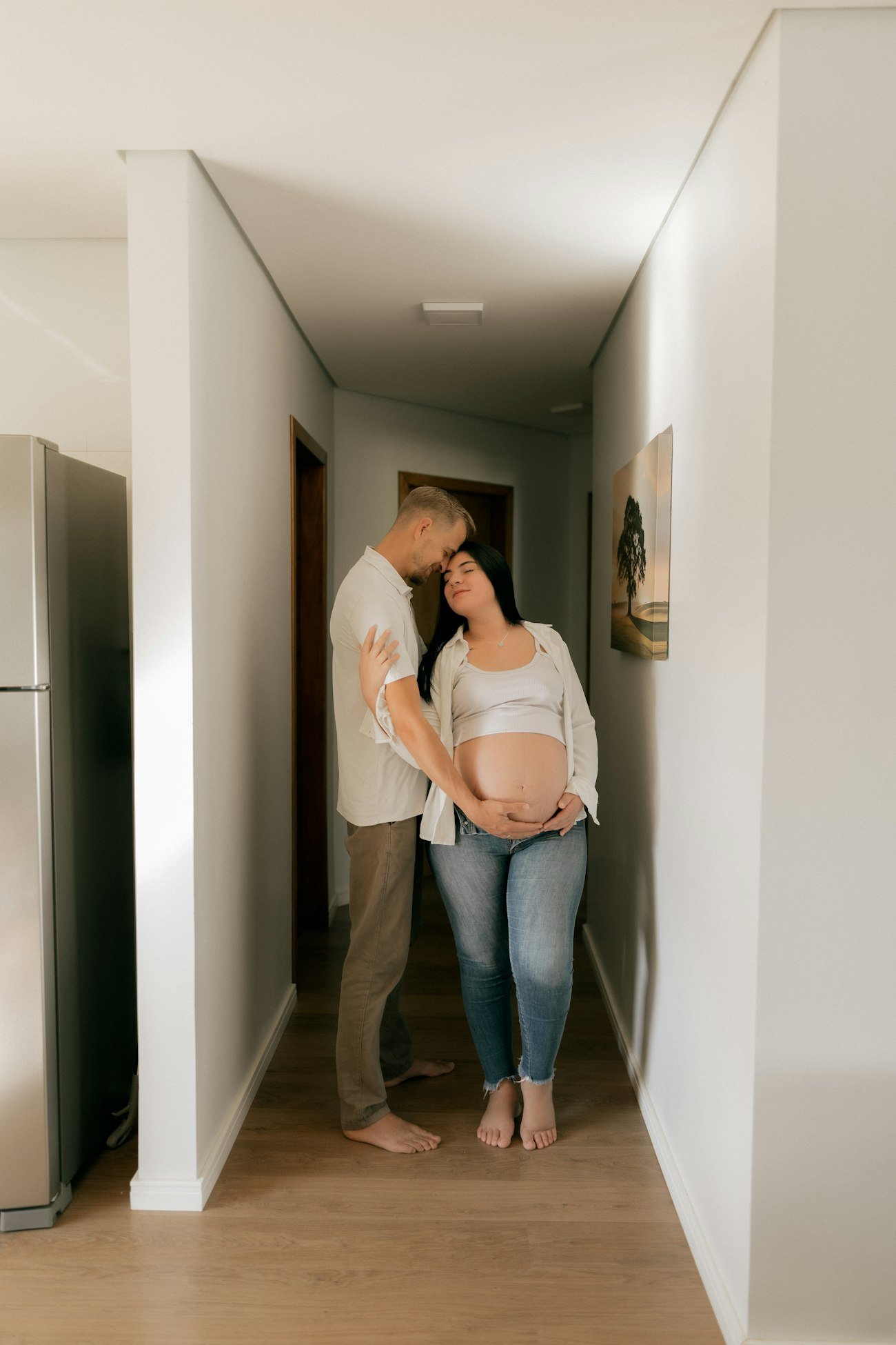 Casal abraçado no corredor claro do seu novo apartamento